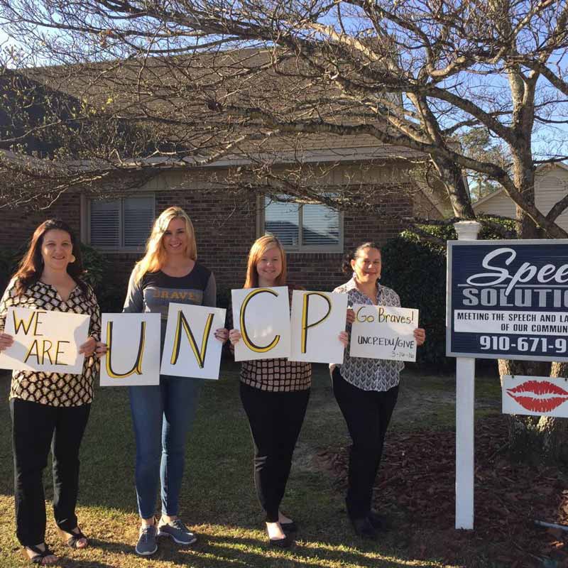 Speech Solutions therapists holding signs that say "We are UNCP"
